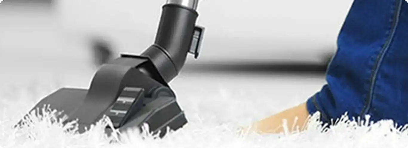 Close-up of a professional vacuuming a white carpet in Rensselaer.